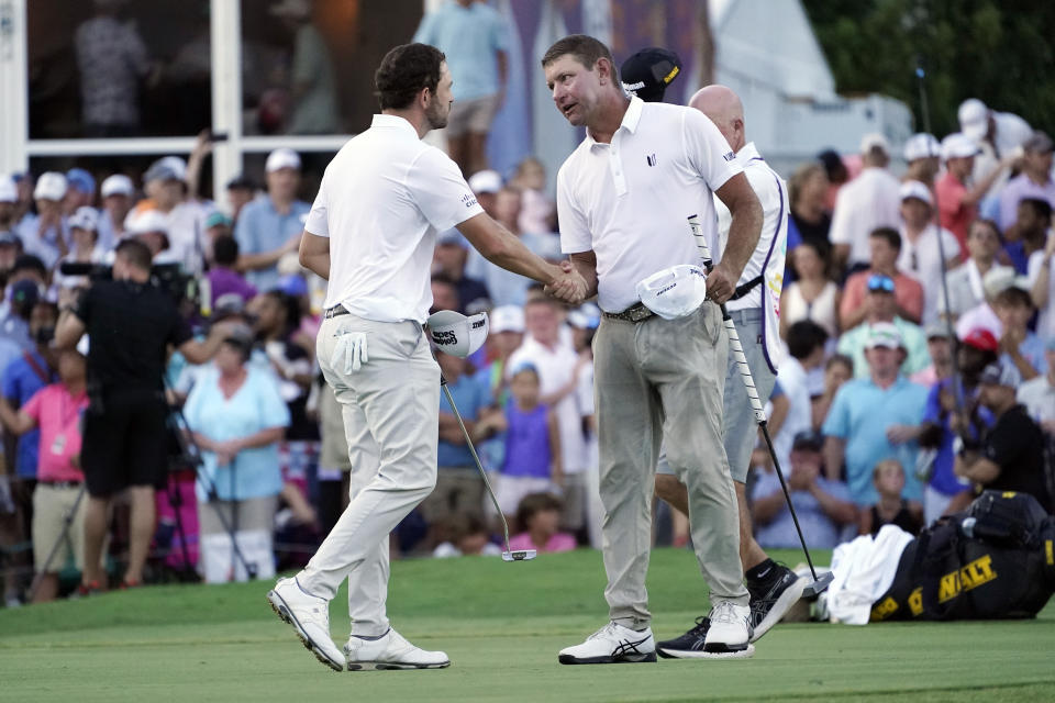 Lucas Glover, right, shakes hands with Patrick Cantlay on the 18th green after Glover won the St. Jude Championship golf tournament in a playoff Sunday, Aug. 13, 2023, in Memphis, Tenn. (AP Photo/George Walker IV)
