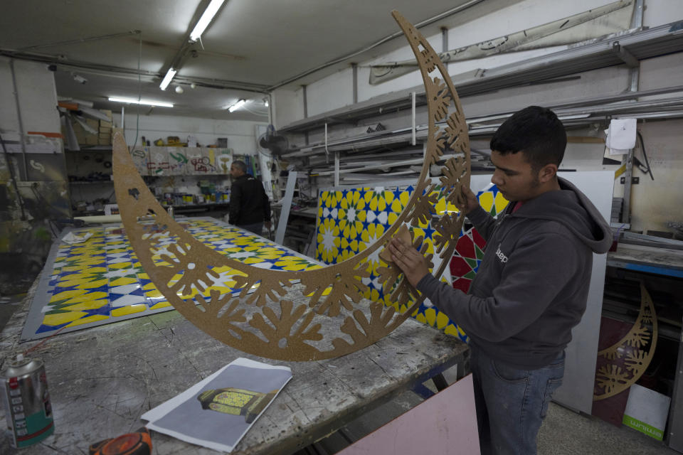 A Palestinian craftsman works on a section of an Islamic style monument that consists of lantern and a crescent, two symbolic icons of the Islamic holy month of Ramadan, in the West Bank city of Ramallah, Tuesday, March 29, 2022. The monument is built by the municipality of Ramallah to decorate a main square at the center of the city, where it will be illuminated during a mass event to celebrate the upcoming Ramadan. (AP Photo/Nasser Nasser)
