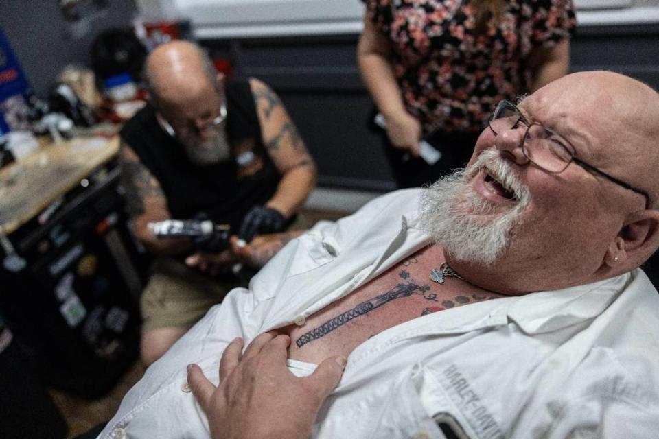 Paul Elkins of Rock Hill laughs as he shows off a zipper tattoo over an open heart surgery scar as tattoo artist Jeff Brown does more work on his right arm at Tattoo Bill’s in Charlotte.