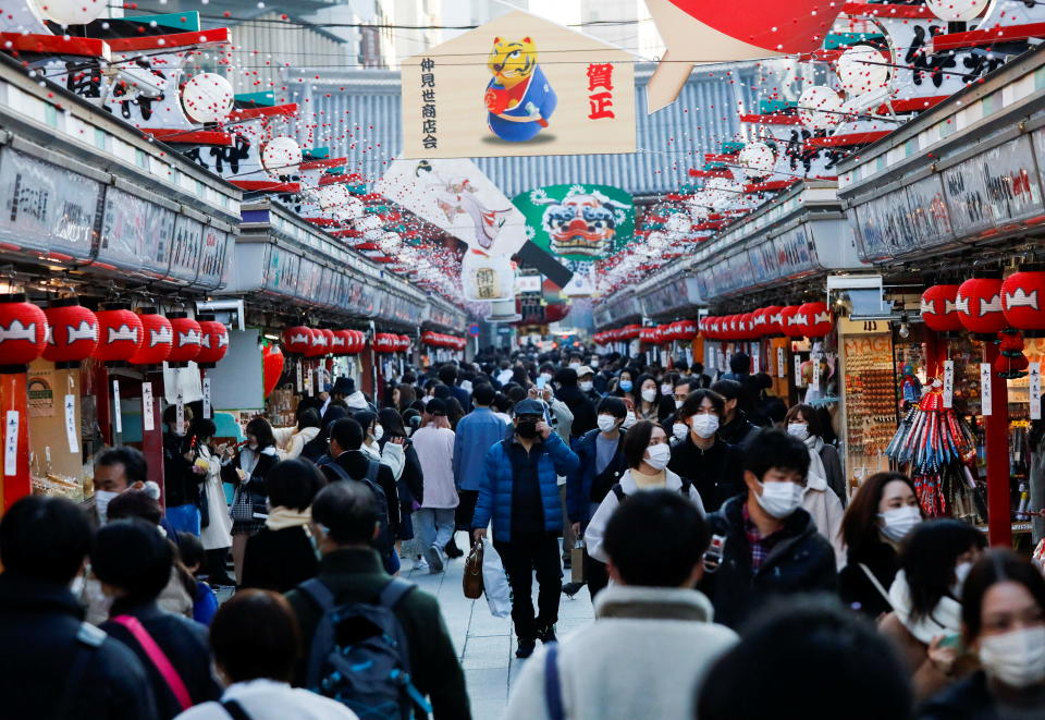 2021年12月24日、日本の東京でコロナウイルス（COVID-19）の大流行に見舞われる人気の観光スポット、浅草の浅草寺に続く中見通りで、保護フェイスマスクを着用した訪問者が新年の装飾の下を歩きます。ロイター/加藤伊佐