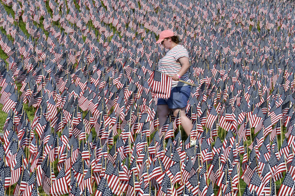 A volunteer walks through a field of American flags planted on Boston Common ahead of Memorial Day, Wednesday, May 26, 2021, in Boston. After more than a year of isolation, American veterans are embracing plans for a more traditional Memorial Day. They say wreath-laying ceremonies, barbecues at local vets halls and other familiar events are a welcome chance to reconnect with fellow service members and renew solemn traditions honoring the nation’s war dead. (AP Photo/Josh Reynolds)