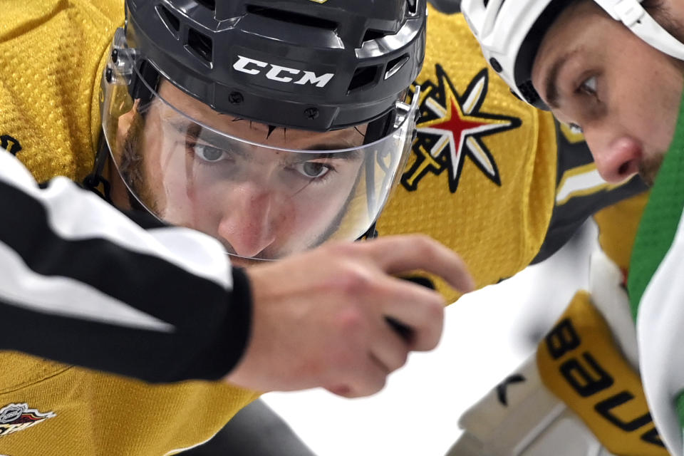 Vegas Golden Knights center Nicolas Roy, left, and Dallas Stars left wing Jamie Benn (14) eye the puck as they for a faceoff during the second period of an NHL hockey game Wednesday, Dec. 8, 2021, in Las Vegas. (AP Photo/David Becker)