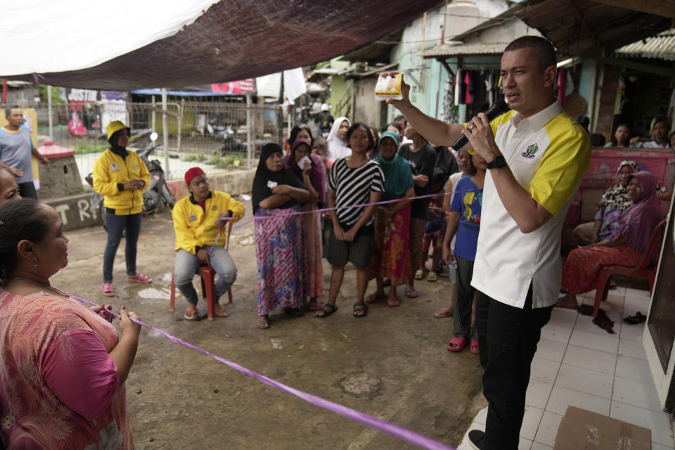 Rian Ernest, a Golkar Party candidate, shows his campaign cards during a campaign rally at a lower-income neighborhood in Jakarta, Indonesia, on Jan. 19, 2024. Christians like Ernest face questions about their faith in the world's third-largest democracy, which will stage presidential and legislative elections Feb. 14. (AP Photo/Dita Alangkara)