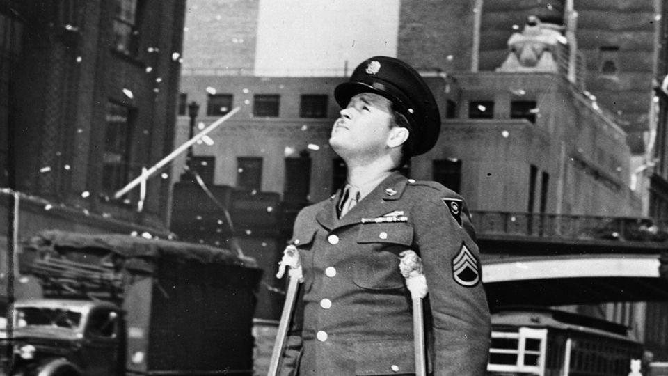 A wounded American serviceman attends a ticker tape parade in New York City on May 7, 1945, following press reports of the unconditional surrender of Germany. - Fox Photos/Getty Images