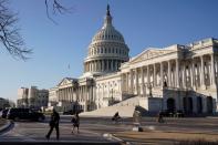 People walk past the U.S. Capitol before the House of Representatives is expected to pass a resolution appointing managers for Senate impeachment trial of President Trump in Washington