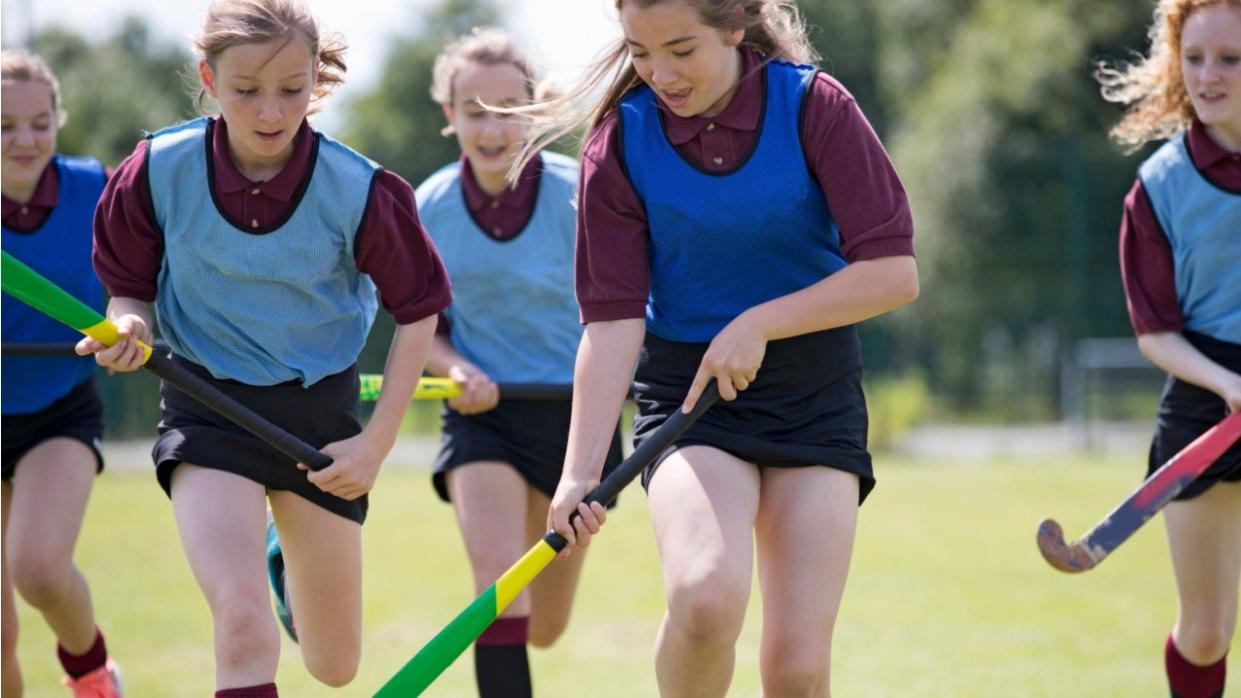 girls playing field hockey