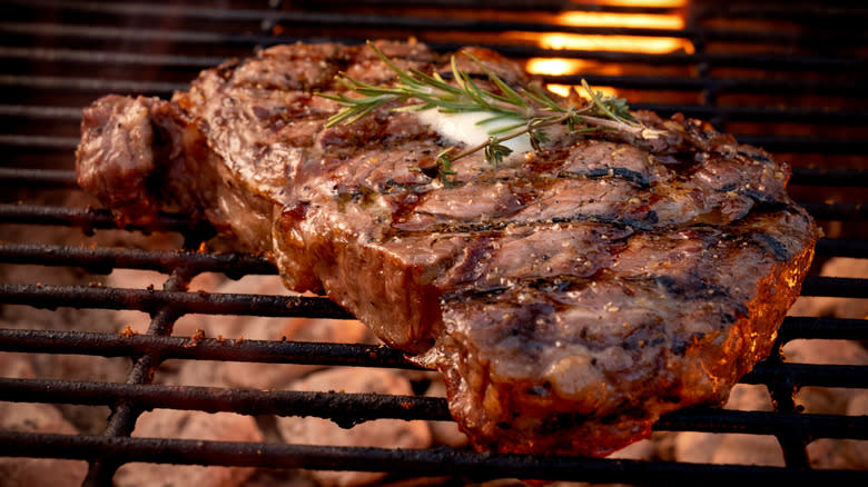 Ribeye steak on grill with butter and rosemary