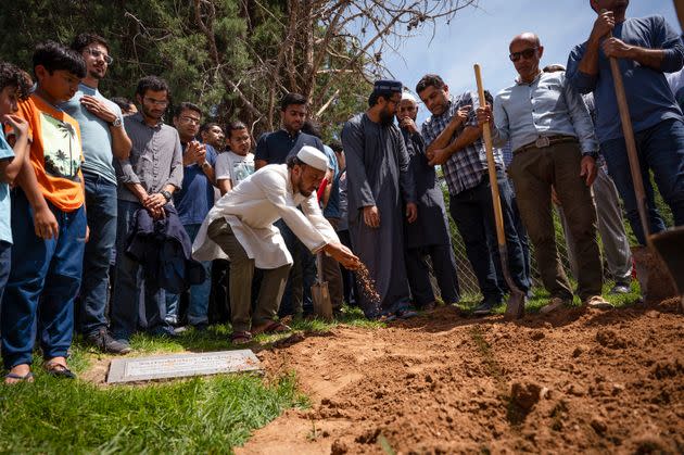 People sprinkle dirt over the grave of Muhammad Afzaal Hussain, 27, at Fairview Memorial Park in Albuquerque on Friday. A funeral service was also held for Hussain and for Aftab Hussein, 41, at the Islamic Center of New Mexico. Both men were killed near their homes six days apart. (Photo: via Associated Press)