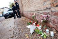 Police officers stand next to the flowers and candles outside the synagogue in Hall