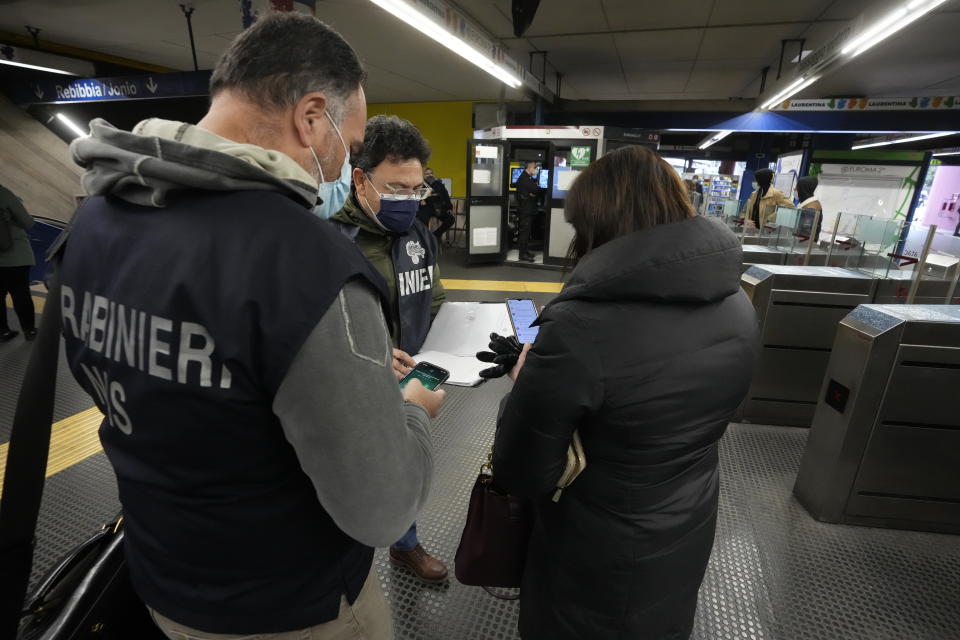 Carabinieri policemen check the green health pass of public transportation passengers in Rome, Monday, Dec. 6, 2021, on the first day a super green health pass went into effect. Italian police can check whether diners in restaurants or bars have a "super" green health pass certifying that they are either vaccinated or have recently recovered from the virus. (AP Photo/Andrew Medichini)