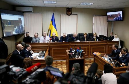 People attend the trial of former riot police force members suspected of killing participants of the 2014 anti-government and pro-European Union mass protests, as Ukraine's former President Viktor Yanukovich giving evidence via a video link is seen on the screens, at a court building in Kiev, Ukraine, November 25, 2016. REUTERS/Valentyn Ogirenko