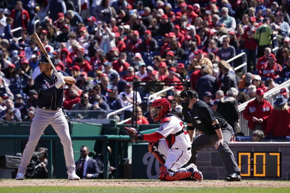A pitch clock, bottom right, is seen behind Atlanta Braves' Matt Olson, from left, Washington Nationals catcher Keibert Ruiz and home plate umpire Dan Bellino during an opening day baseball game at Nationals Park, Thursday, March 30, 2023, in Washington. (AP Photo/Alex Brandon)