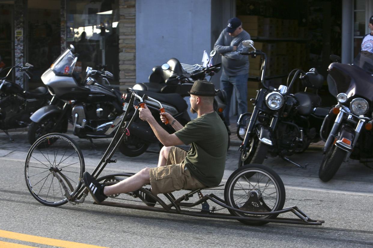 A man rides a bicycle down Main Street in Daytona, FL during the beginning of Bike Week on March 5, 2021. (Sam Thomas/Orlando Sentinel)