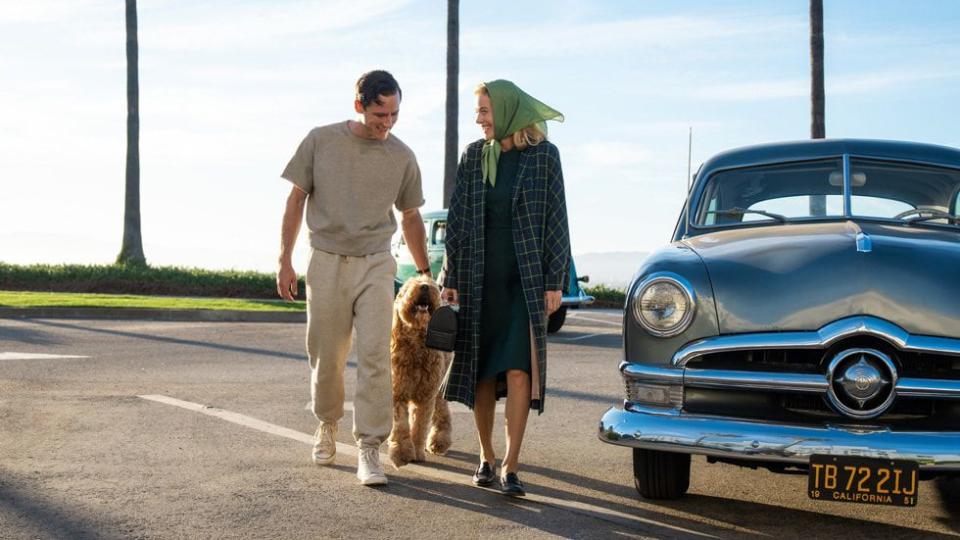 a man and a woman walking a dog on a road