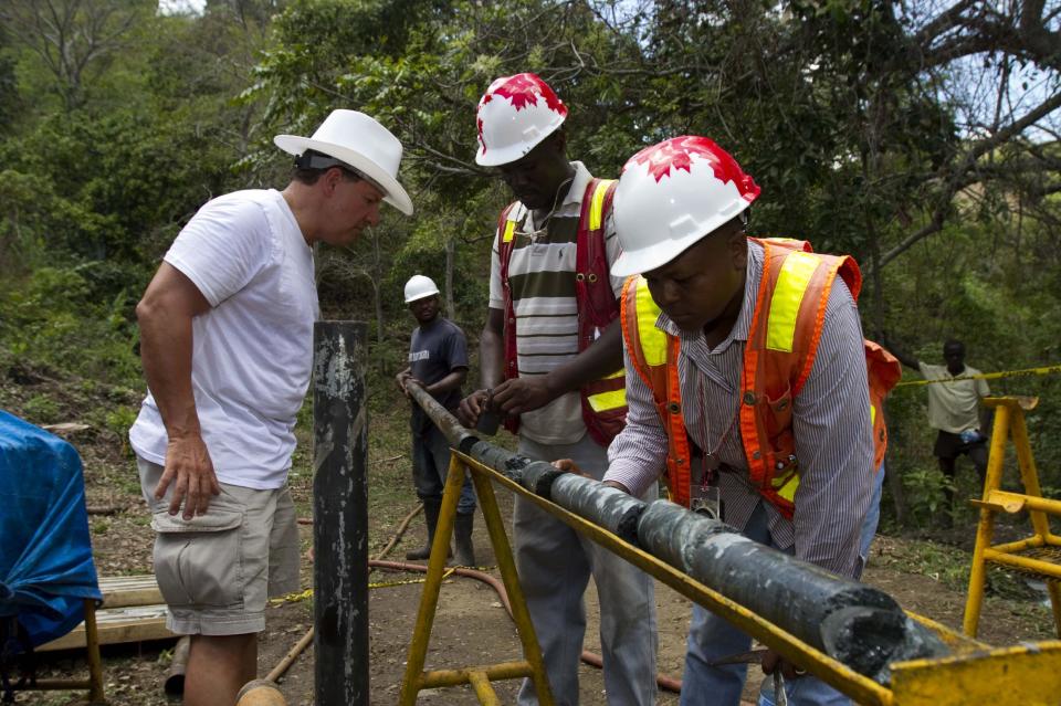 In this April 10, 2012 photo, Daniel Hachey, president resources MAJESCOR, left, and geologist Francisque Pierre, right, examine samples of stone for minerals and metals at a drill site in the department of Trou Du Nord, Haiti. Haiti's land may yet hold the solution to centuries of poverty: there is gold hidden in its hills, and silver and copper too. Now, two mining companies are drilling around the clock to determine how to get those metals out, and how much it might cost.  (AP Photo/Dieu Nalio Chery)