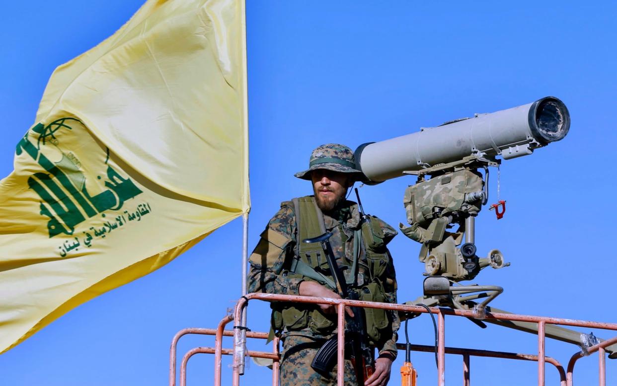 A Hizbollah flag flutters at a watchtower near the Lebanon-Syria border - AP