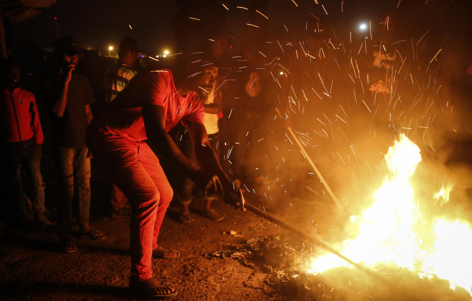 In this photo taken Monday, June 1, 2020, residents burn fires late at night on a street to protest the death of James Mureithi, a homeless man who protesters alleged was shot dead by police during the nightly dusk-to-dawn curfew established to curb the spread of the coronavirus, in the Mathare slum, or informal settlement, of Nairobi, Kenya. Hundreds of people in Mathare left their homes and burnt tires on the streets in the latest outrage over alleged police brutality, with a rights activist claiming that 19 Kenyans from low-income neighborhood have died from police actions in enforcing the curfew. (AP Photo/Brian Inganga)