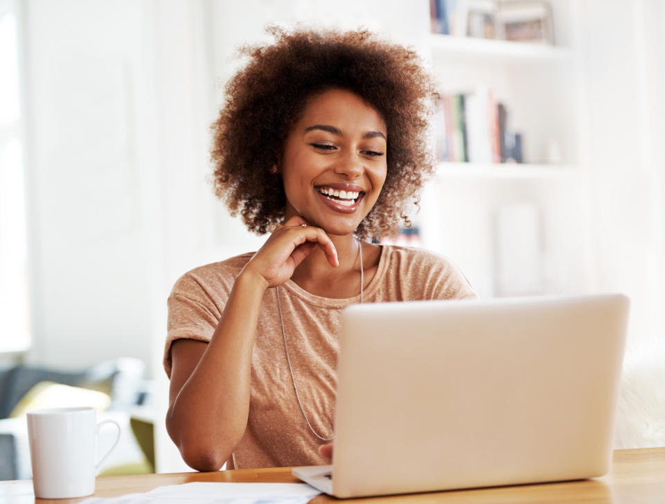 A laughing ethnic woman looking at her laptop