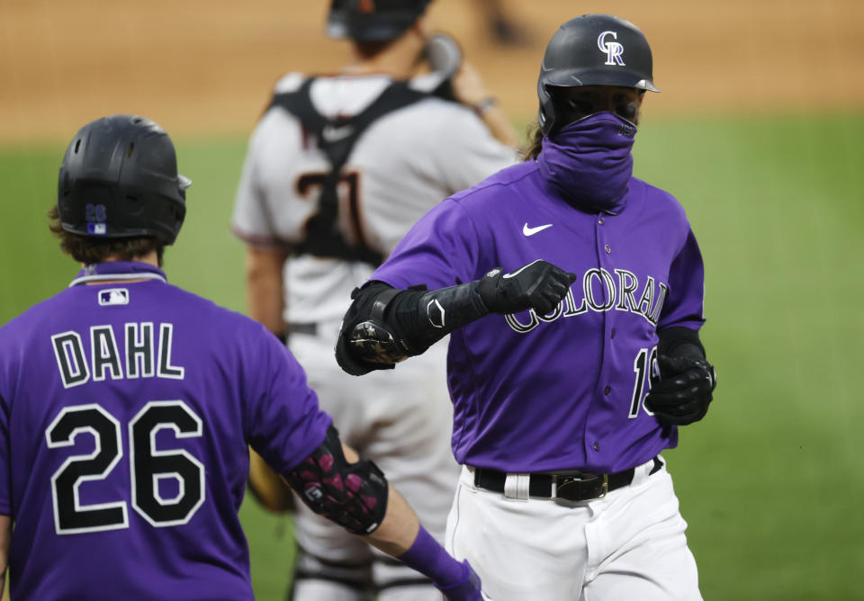 Colorado Rockies' Charlie Blackmon, right, is congratulated by David Dahl as he scores on a single by Matt Kemp off Arizona Diamondbacks starting pitcher Robbie Ray in the third inning of a baseball game Monday, Aug. 10, 2020, in Denver. (AP Photo/David Zalubowski)