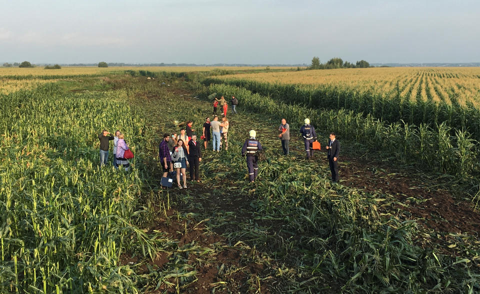 Rescuers, passengers and crew stand in the field after being evacuated from the jet. (Reuters)