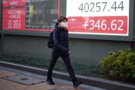 A person walks in front of an electronic stock board showing Japan's Nikkei 225 index at a securities firm Monday, March 4, 2024, in Tokyo. Japan's Nikkei 225 share benchmark has topped 40,000 for the first time as strong demand for technology shares keeps pushing the index higher.(AP Photo/Eugene Hoshiko)