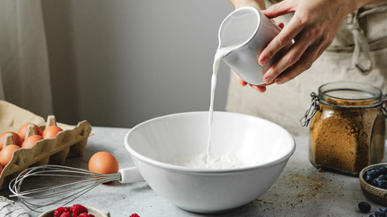 pouring milk into bowl for pancake mix