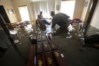 FILE - In this Sept. 2, 2017, file photo, Paul England Jr., right, helps Michael Brown move bedroom furniture floating in his flooded home in the aftermath of Tropical Storm Harvey, in Port Arthur, Texas. Many families across Texas are still struggling a year after Hurricane Harvey's destructive winds and biblical rainfall. But daily life has for the most part returned to normal routines in many of the cities hit hardest by the storm. (AP Photo/Gerald Herbert, File)