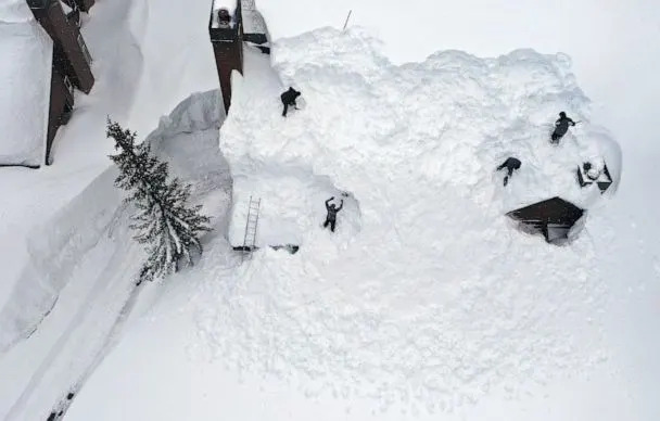 PHOTO: Workers remove snow from the roof of a condominium complex in the Sierra Nevada mountains, after yet another storm system brought heavy snowfall, March 29, 2023, in Mammoth Lakes, Calif. (Mario Tama/Getty Images)