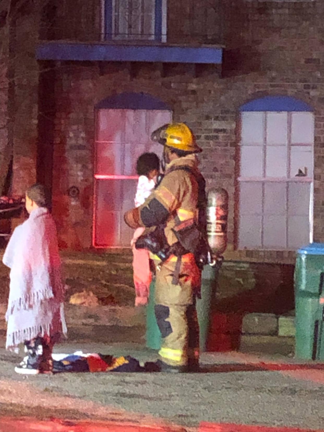 An Athens-Clarke County firefighter holds a child after residents in nearby apartments were evacuated during a fire Tuesday in northwest Athens.