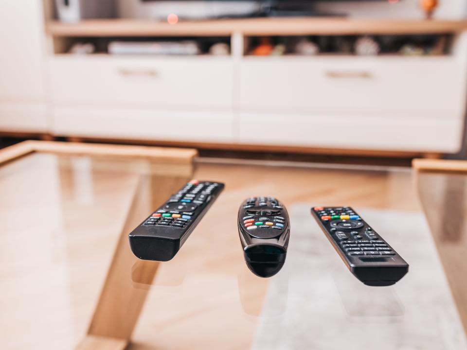 Three remote controls on a coffee table in front of an entertainment center