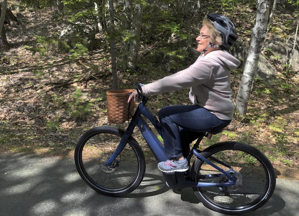 In this June 8, 2019 photo, Janice Goodwin rides her electric-assist bicycle on a paved road in Acadia National Park at Bar Harbor, Maine. E-bikes such as hers are allowed on paved roads but are banned on carriage paths and bicycle paths in the park. (AP Photo/David Sharp)