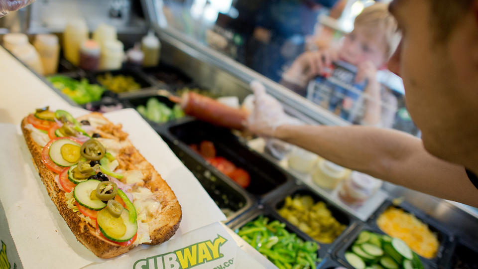 Un lavoratore fa un panino all'interno della catena di fast food Subway ad Hannover, Germania, 21 agosto 2015. Il panino della catena di fast food festeggerà il suo cinquantesimo compleanno il 50 agosto 28.