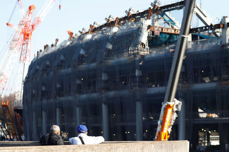 Men looks at the construction site of the New National Stadium, main stadium of Tokyo 2020 Olympics and Paralympics, in Tokyo, Japan December 22, 2017. REUTERS/Issei Kato