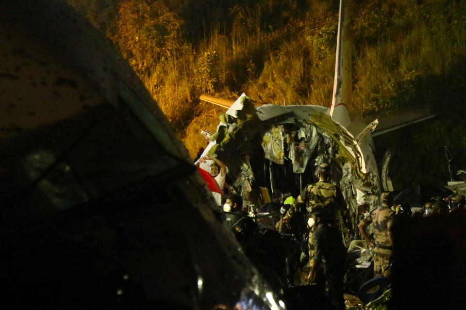 First responders inspect the wreckage of an Air India Express jet, which was carrying more than 190 passengers and crew from Dubai, after it crashed by overshooting the runway at Calicut International Airport in Karipur, Kerala, on August 7, 2020. - At least 14 people died and 15 others were critically injured when a passenger jet skidded off the runway after landing in heavy rain in India, police said on August 7. (Photo by Favas JALLA / AFP) (Photo by FAVAS JALLA/AFP via Getty Images)