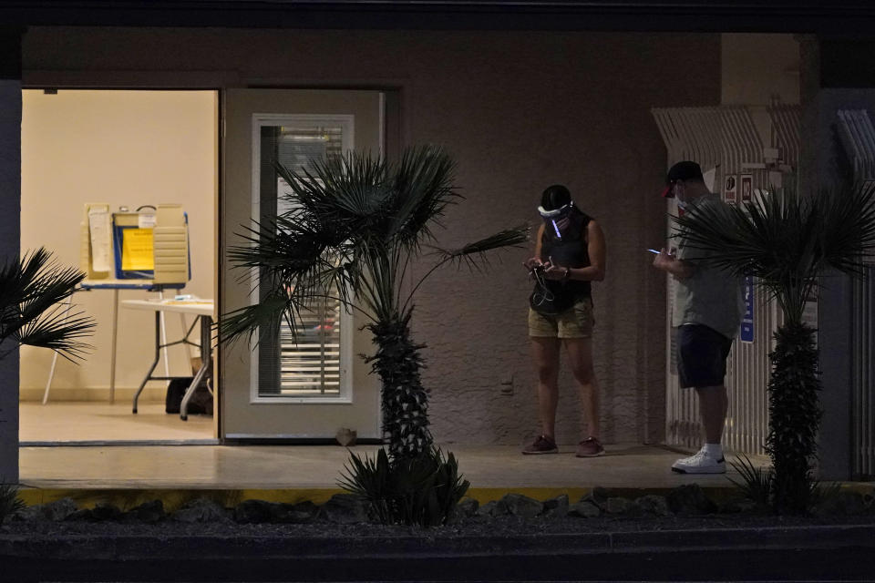 Poll workers check their phones as they wait for voters at a local polling station Tuesday, Nov. 3, 2020 in Tucson, Ariz. (AP Photo/Ross D. Franklin)