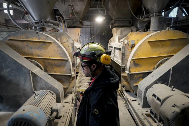 A worker stands beside the mixing machines at the start of a production line creating concrete blocks designed with liquid carbon dioxide as an ingredient at the Glenwood Mason Supply Company, Tuesday, April 18, 2023, in the Brooklyn borough of New York. New York is forcing buildings to clean up, and several are experimenting with capturing carbon dioxide, cooling it into a liquid and mixing it into concrete where it turns into a mineral. (AP Photo/John Minchillo)