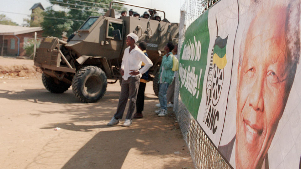 People next to an armored vehicle and a poster of Nelson Mandela in South Africa – April 25, 2024