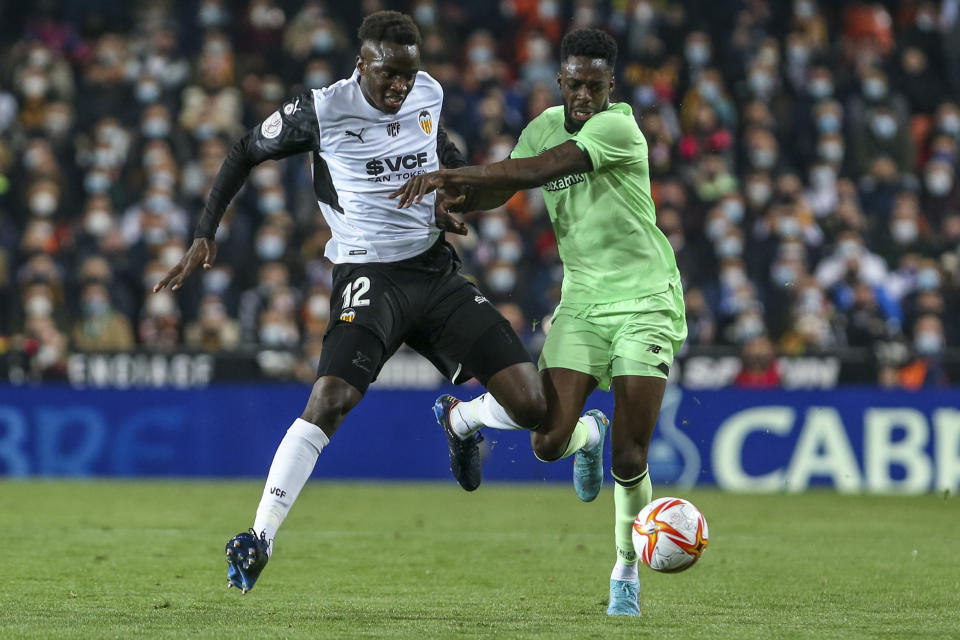 ARCHIVO - Mouctar Diakhaby (izquierda) del Valencia pugna por el balón con Iñaki Williams del Athletic Bilbao en las semifinales de la Copa del Rey, el 2 de marzo de 2022. (AP Foto/Alberto Saiz)