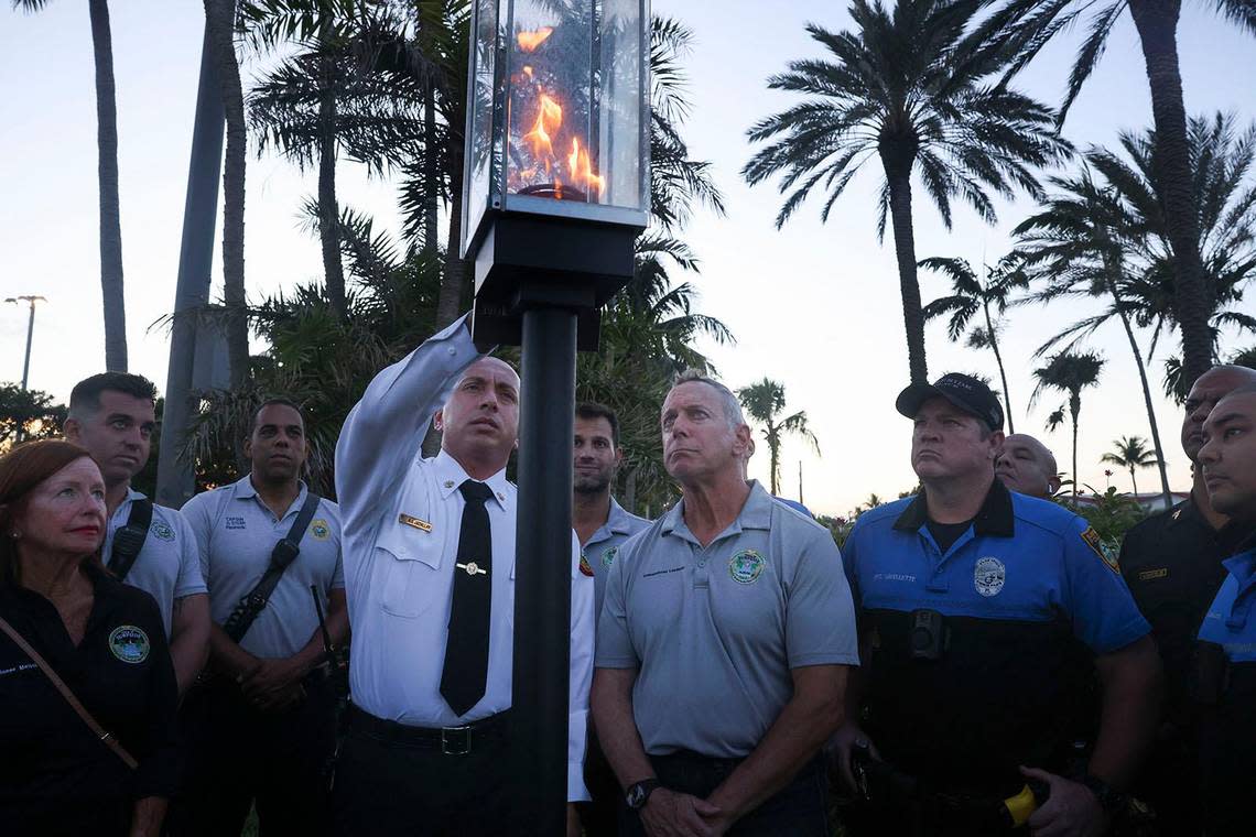 Miami Dade Fire Rescue Deputy Fire Chief of Emergency Operations Ray Jadallah extinguishes the symbolic flame during a ceremony with other firefighters and community members in front of where Champlain Towers South stood. Wednesday marked one year since the last of the 98 victims of the collapse was recovered.