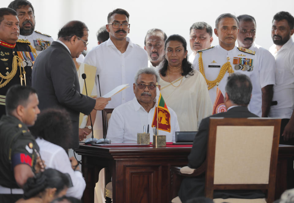 Sri Lanka's newly elected president Gotabaya Rajapaksa, center seated, looks on as secretary to the president Udaya Seneviratne, left, reads a document during the swearing in ceremony held at the 140 B.C Ruwanweli Seya Buddhist temple in ancient kingdom of Anuradhapura in northcentral Sri Lanka Monday, Nov. 18, 2019. The former defense official credited with ending a long civil war was Monday sworn in as Sri Lanka’s seventh president after comfortably winning last Saturday’s presidential election. (AP Photo/Eranga Jayawardena)