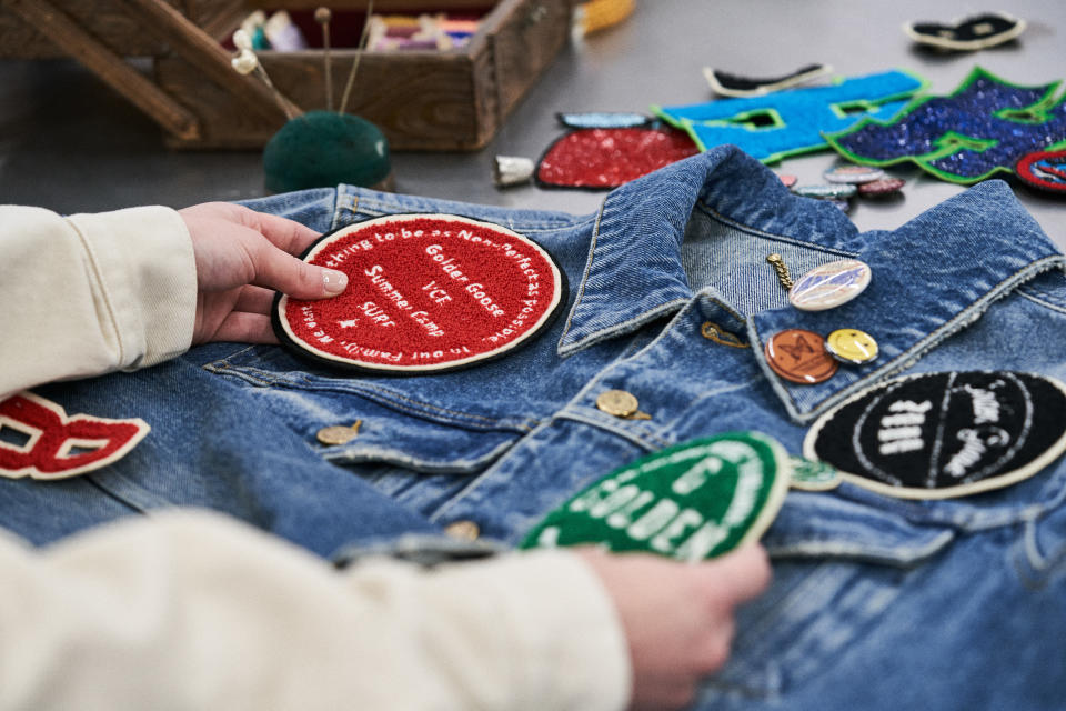 A tailor works on embellishments for a Golden Goose custom jacket.