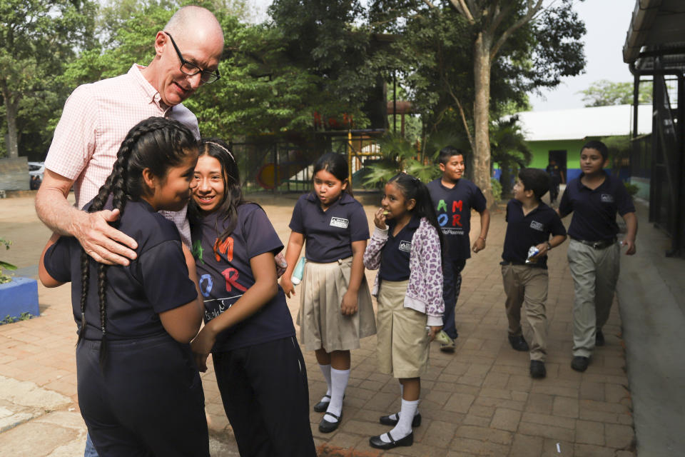 Pastor Kenton Moody, left, is greeted by Salvadoran children at the Hosanna School, an institution run by the Assemblies of God Church, in an area once controlled by gangs, in Santa Ana, El Salvador, Wednesday, May 3, 2023. Moody's evangelical church, “La Puerta Abierta,” which means “open door,” is a cornerstone for social projects funded mostly by U.S. donors. His foundation sponsors houses for homeless people, a clinic and a school. (AP Photo/Salvador Melendez)