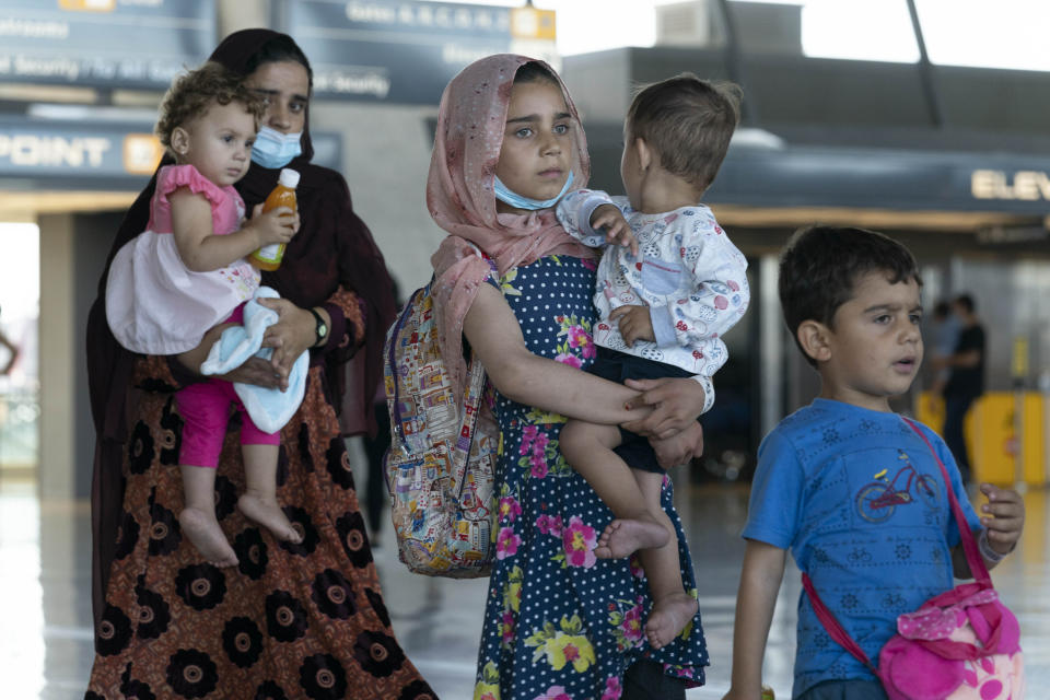 Families evacuated from Kabul, Afghanistan, walk through the terminal before boarding a bus after they arrived at Washington Dulles International Airport, in Chantilly, Va., on Thursday, Sept. 2, 2021. (AP Photo/Jose Luis Magana)