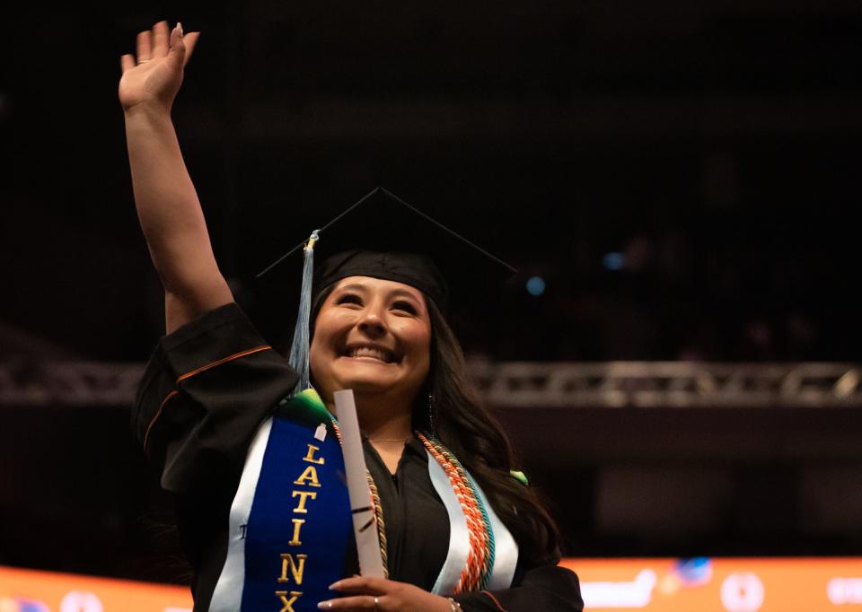 UT graduate Noelia Delgado Rosas waves to her family after receiving her degree from the College of Education on Saturday in Moody Center.