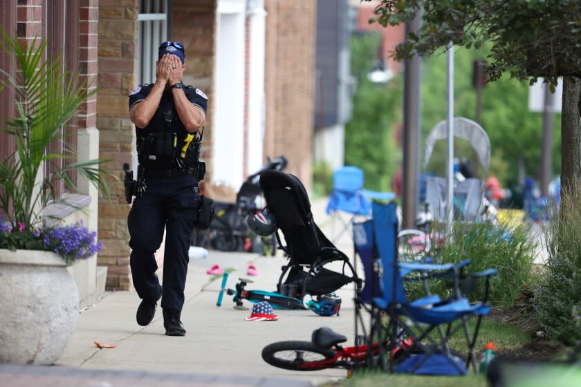 A Lake County police officer walks down Central Ave in Highland Park, Ill. on Monday