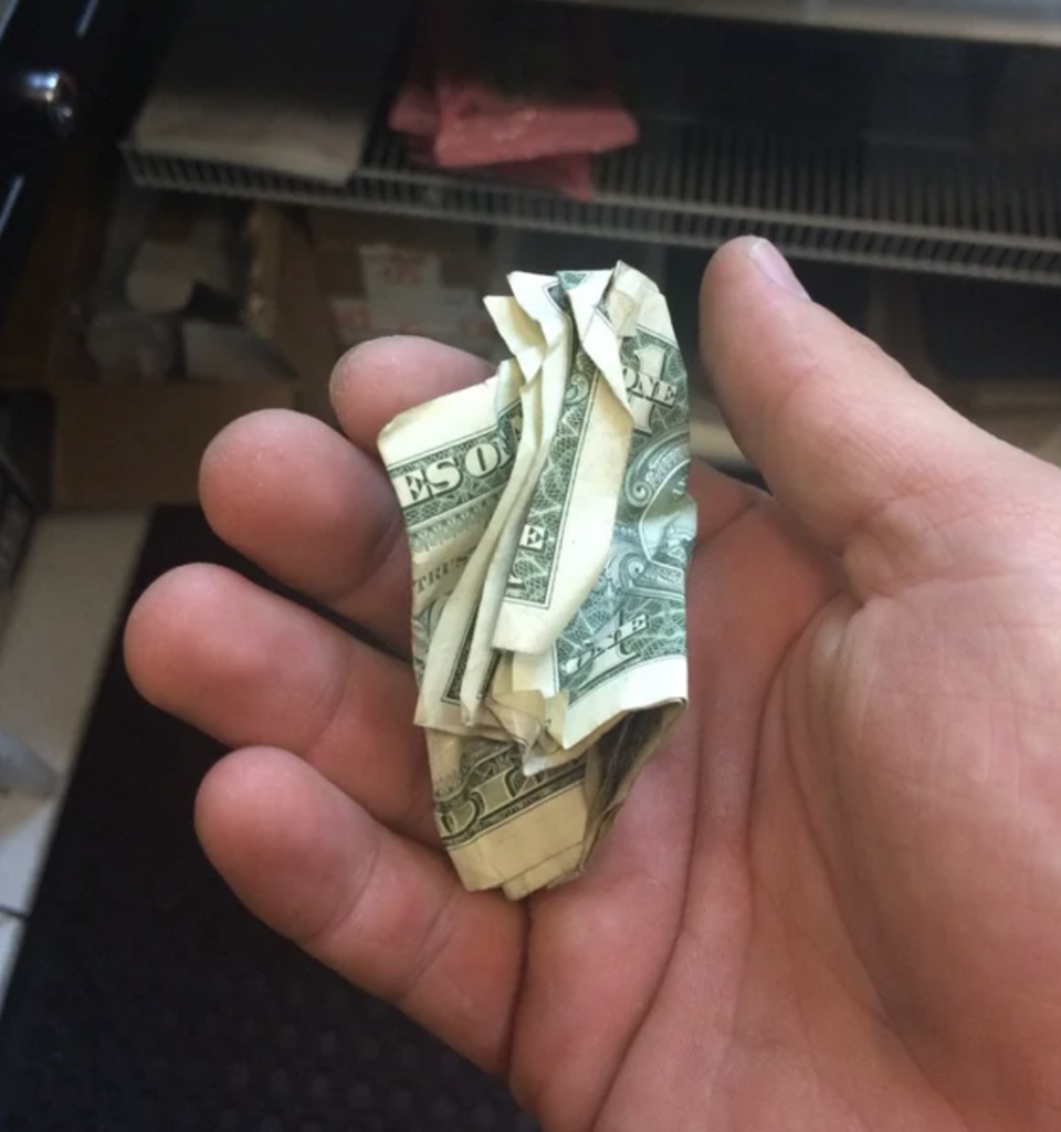 A cashier is holding crumpled money