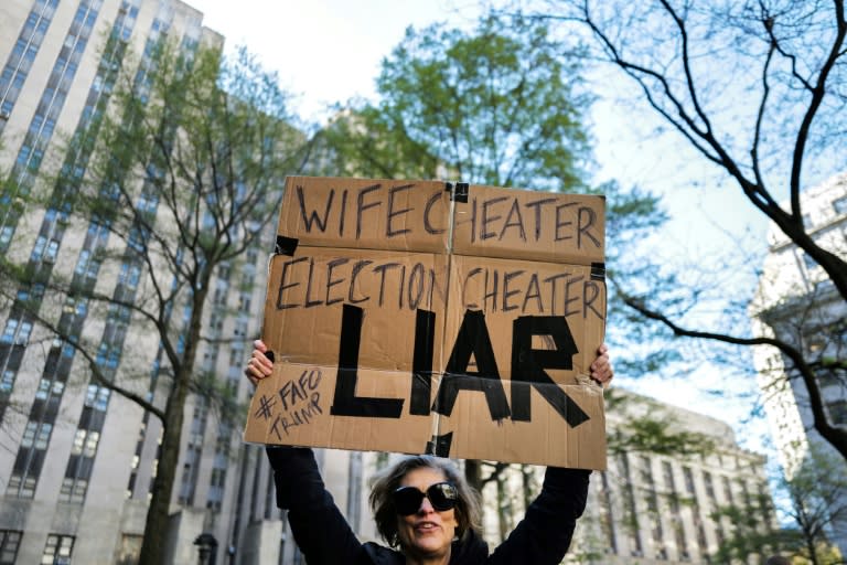 A protestor holds up a sign outside the courthouse where former US president Donald Trump is on trial (Charly TRIBALLEAU)