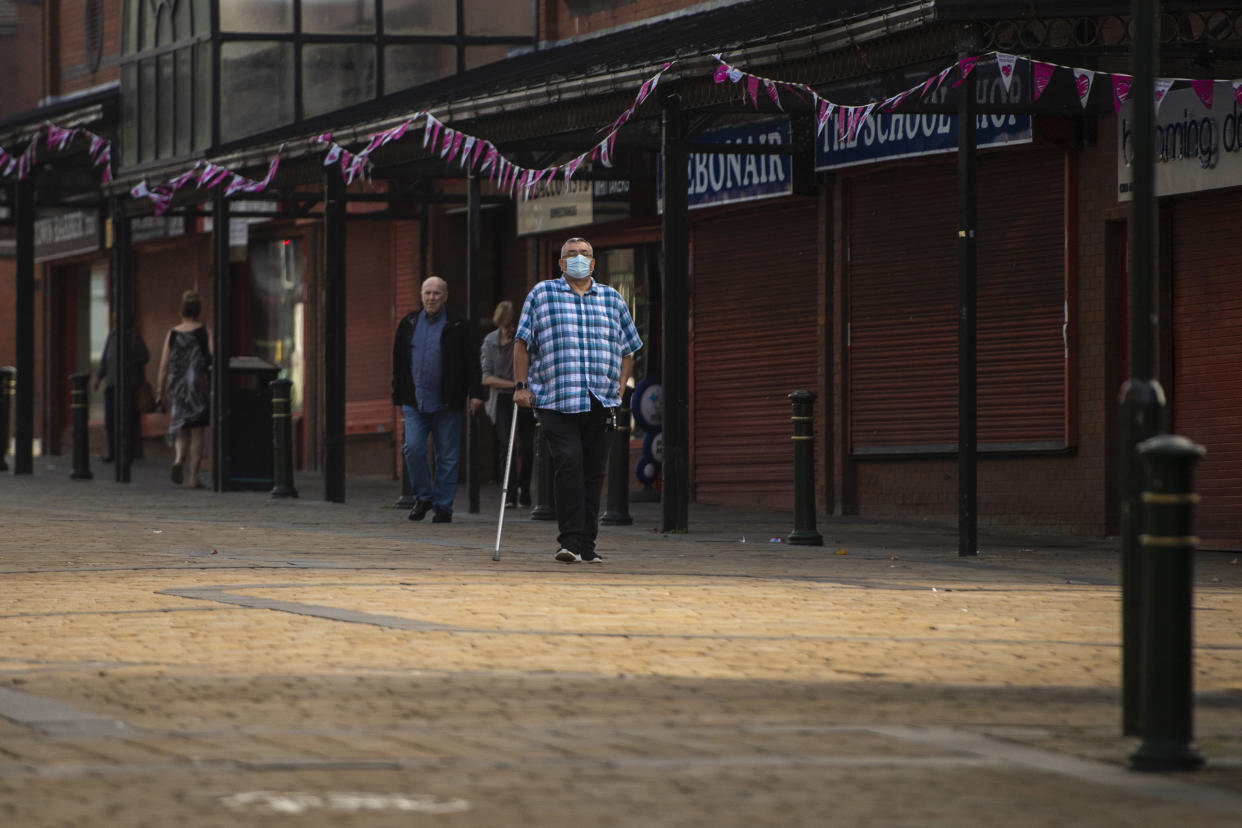 OLDHAM, ENGLAND - AUGUST 13: A man wearing a face mask walks through Oldham town centre on August 13, 2020 in Oldham, England. The town is on the brink of a local lockdown after a surge in coronavirus cases has left it the worst affected area in England. (Photo by Anthony Devlin/Getty Images)