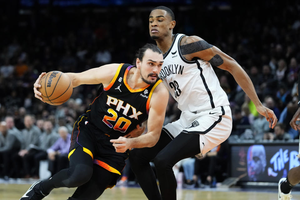 Phoenix Suns forward Dario Saric (20) drives past Brooklyn Nets center Nic Claxton (33) during the second half of an NBA basketball game, Thursday, Jan. 19, 2023, in Phoenix. (AP Photo/Matt York)