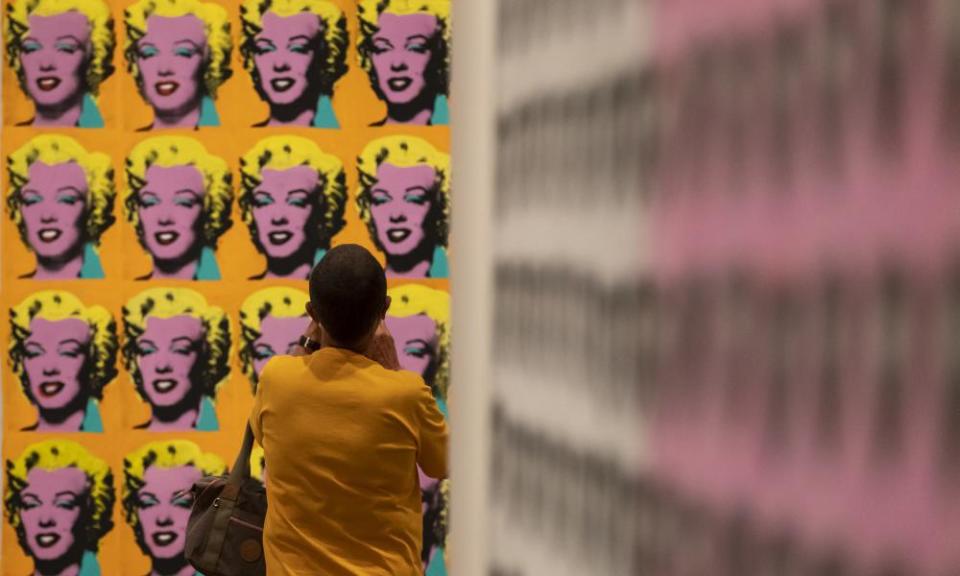 A visitor wearing a face mask views artworks by Andy Warhol during an exhibition at Tate Modern.